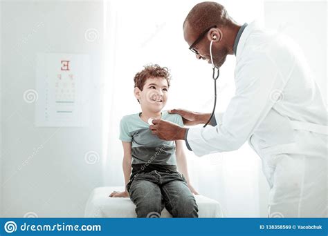 Positive Delighted Young Doctor Examining His Patient Stock Image