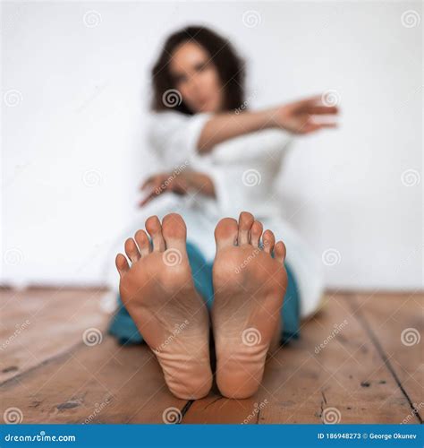 Women S Bare Feet In The Foreground The Girl Is Sitting On A Wooden Floor Stock Image Image Of