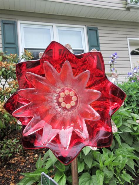 A Red Glass Flower In Front Of A House