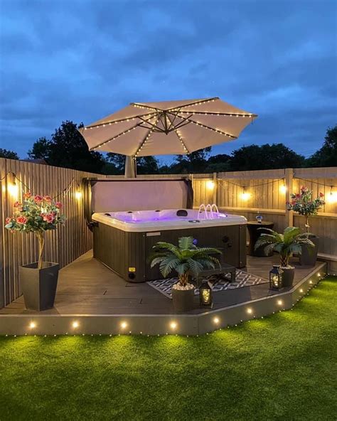 An Outdoor Hot Tub Surrounded By Potted Plants And Lit Up Lights On The