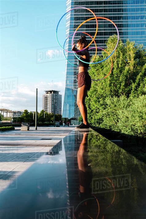 Young Woman Performing Hula Hoop Dance With Four Rings In Downtown