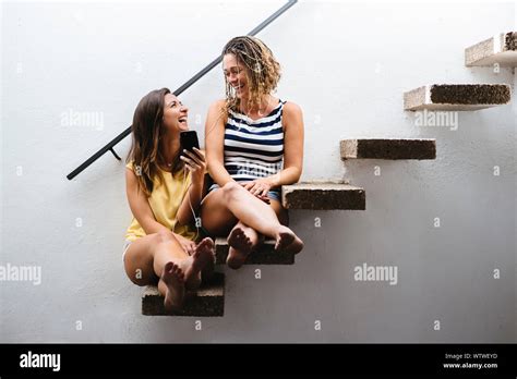 Deux femmes assises dans les escaliers en riant tout en écoutant de la musique Photo Stock Alamy