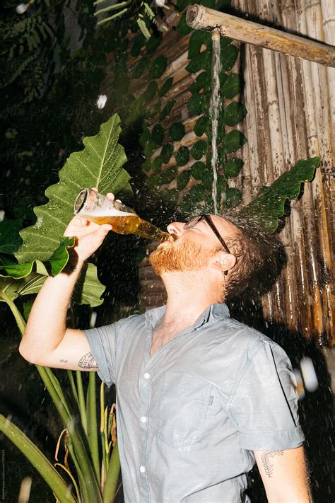 Young Man Drinks Beer Fully Clothed In Outdoor Wild Shower With Large