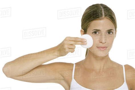 Woman Holding Up Cotton Pad To Cheek Looking At Camera Stock Photo