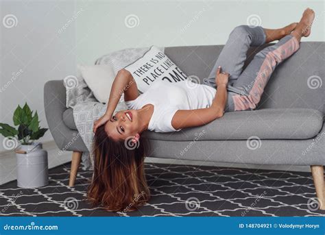 Beautiful Woman Relaxing On A Grey Couch With Head Upside Down Cute Girl Having Fun At Cozy