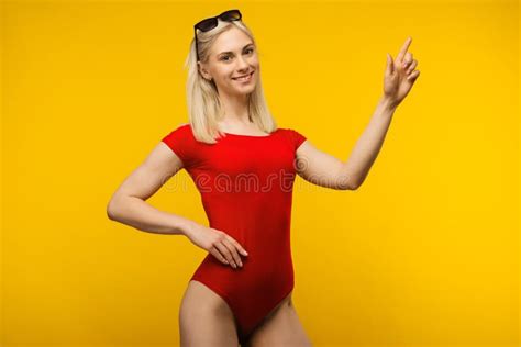 Pretty Blond Lifeguard In Red Swimsuit And Sunglasses Points Finger Up