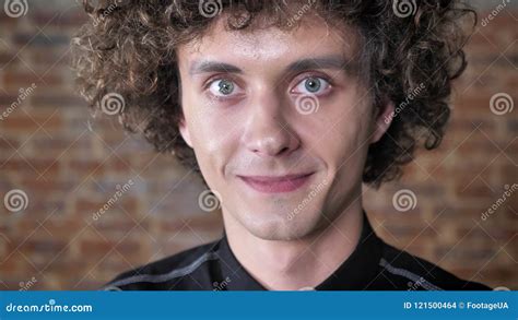 Young Handsome Man With Curly Hair Raising His Eyebrows And Smiling At