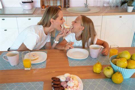 Perfil De Mamá E Hija En La Cocina Mordiendo El Donut En Ambos Lados