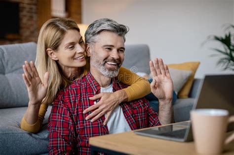 Cheerful Mature European Lady Hugging Male Looking At Pc Waving Hand