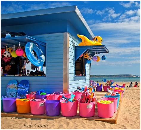 There Are Many Buckets And Toys On The Beach By This Small Shack That