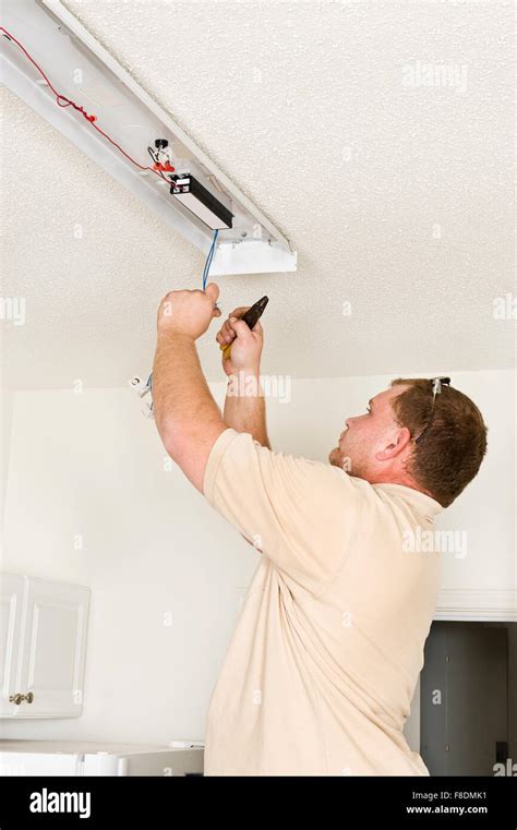 A Male Electrician Installing A Fluorescent Lighting Fixture Stock