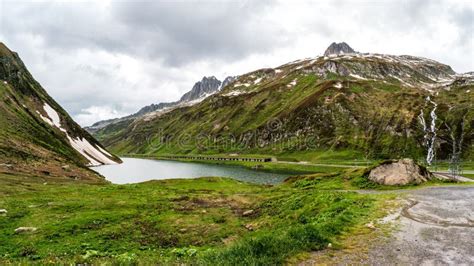 Swiss Alps Mountain Pass Panoramic Scene With Lake And Cloudy Dramatic