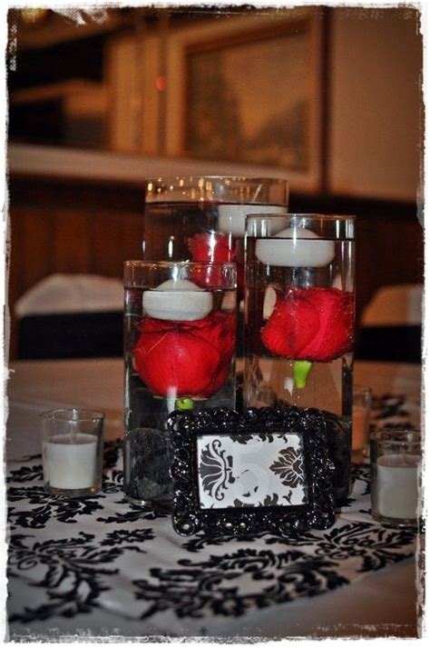 Two Vases Filled With Flowers And Candles On Top Of A Black Tablecloth