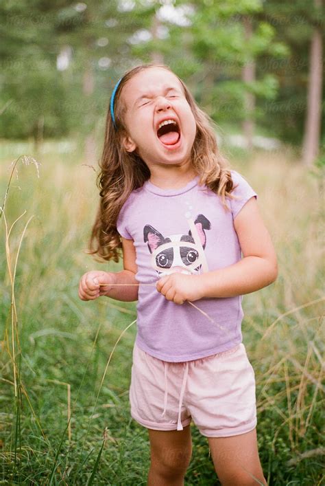 Cute Young Girl Making A Funny Face In A Field By Jakob Lagerstedt