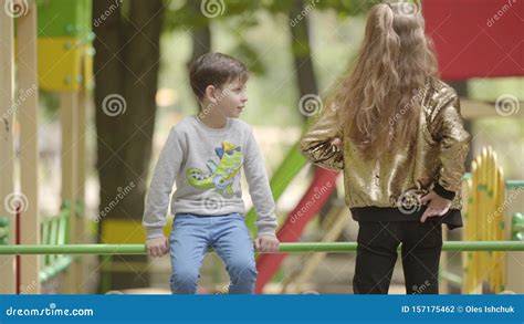 Младший брат и старшая сестра играют и разговаривают на детской площадке Отношения между