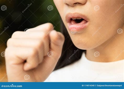 Closeup Of Mouth Of Asian Woman Coughing Into Her Hand To Prevent