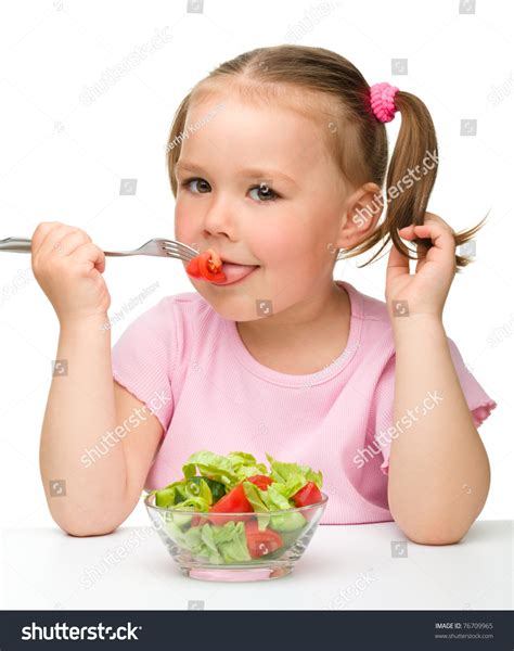 Cute Little Girl Eats Vegetable Salad Using Fork Isolated Over White