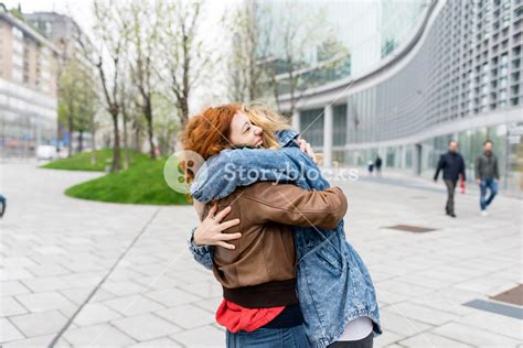 Two Friends Redhead And Blonde Girl Millennials In The Street Of The City And Hugging Friendship