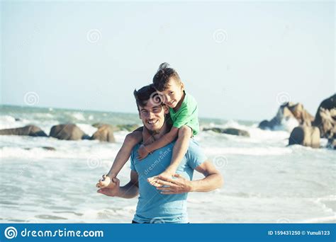 Familia Feliz En La Playa Que Juega Padre Con La Costa De Mar Del Hijo