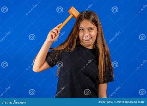 bonita chica preadolescente golpeando su cabeza con un mazo de cocina de madera aislado sobre
