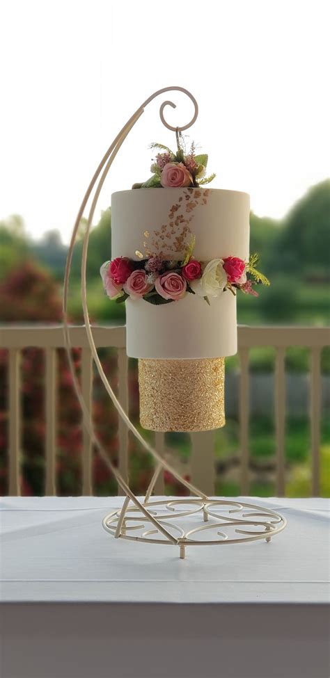 A Three Tiered Cake Sitting On Top Of A White Table Next To A Fence