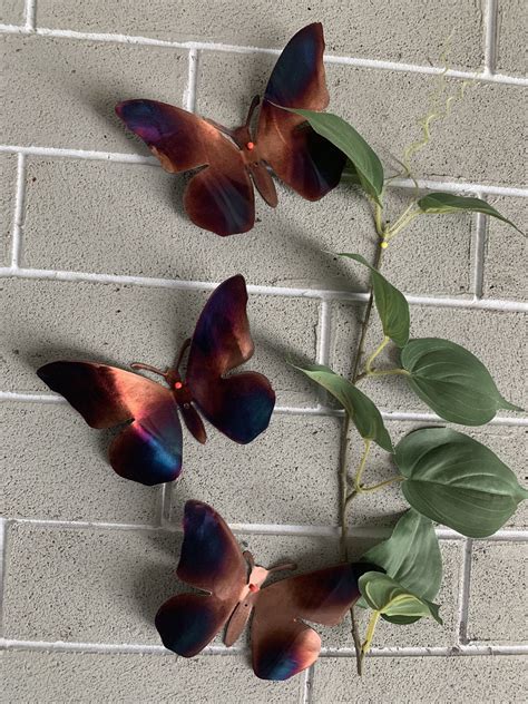 Three Butterflies On A Brick Wall With Green Leaves