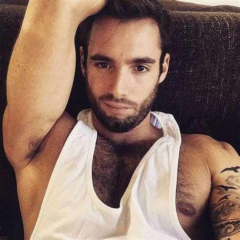 A Man Sitting On A Couch Wearing A Tank Top