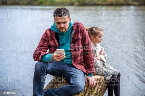 Dad With A Phone In His Hands Does Not Pay Attention To His Little