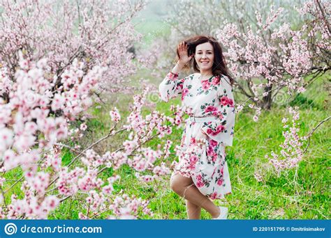 Beautiful Brunette Woman In A Dress With Flowers In Pink Blossoming