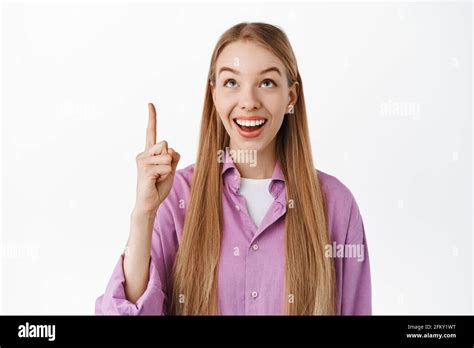 Smiling Excited Blond Girl Looking And Pointing Up With Happy Face