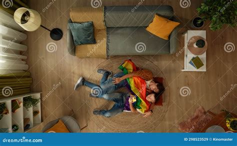 top view shot of a homosexual couple lying on the floor together hugging and taking selfies