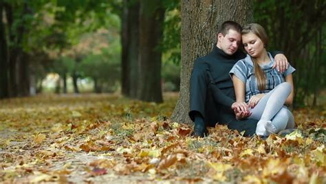 Young Couple Kissing On Fallen Leaves In Autumn Park Stock