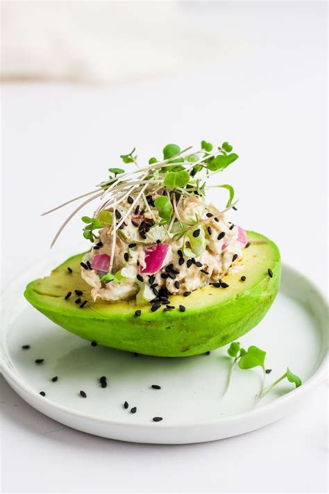 An Avocado Is Topped With Sprouts And Other Toppings On A White Plate