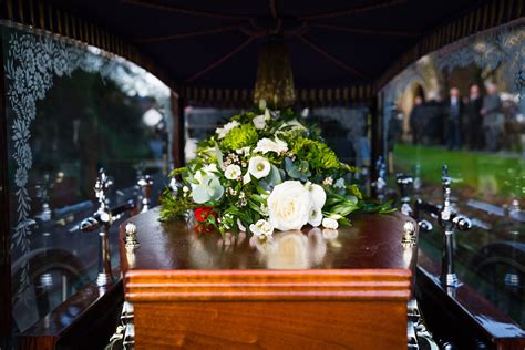 A Wooden Table Topped With White Flowers And Greenery In Front Of A