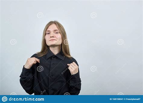 Attractive Young Woman On Gray Wall Pulls Shirt With Fingers Looking