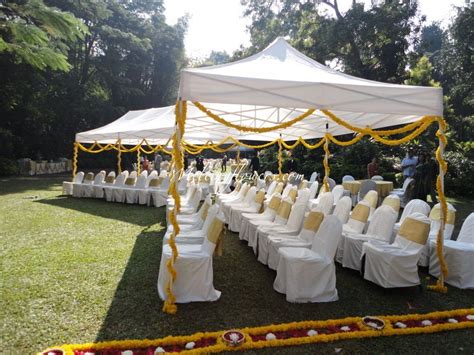an outdoor wedding setup with white linens and yellow sashes on the chairs under a canopy