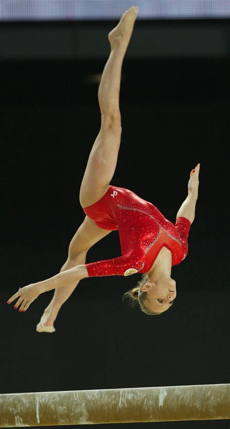 A Woman Is Doing A Handstand On The Balance Beam In A Gymnastics