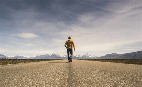 Man Walking On A Road In Remote Landscape In Patagonia Argentina Stock