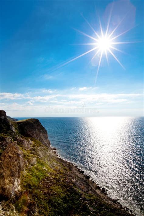 Seascape Of Still Blue Sea Waters Shore Rocky Coastline And Bright Sun