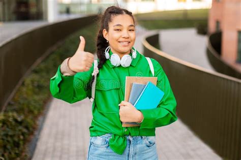 Happy Student Girl Gesturing Thumbs Up Posing With Books And Smiling