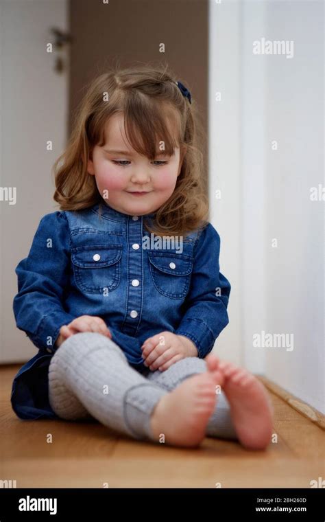 Portrait Of Smiling Toddler Girl Sitting On The Floor At Home Watching