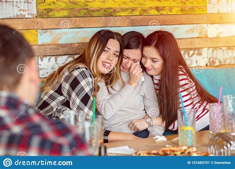 Friends Comforting And Consoling Crying Young Woman Trying To Make Her