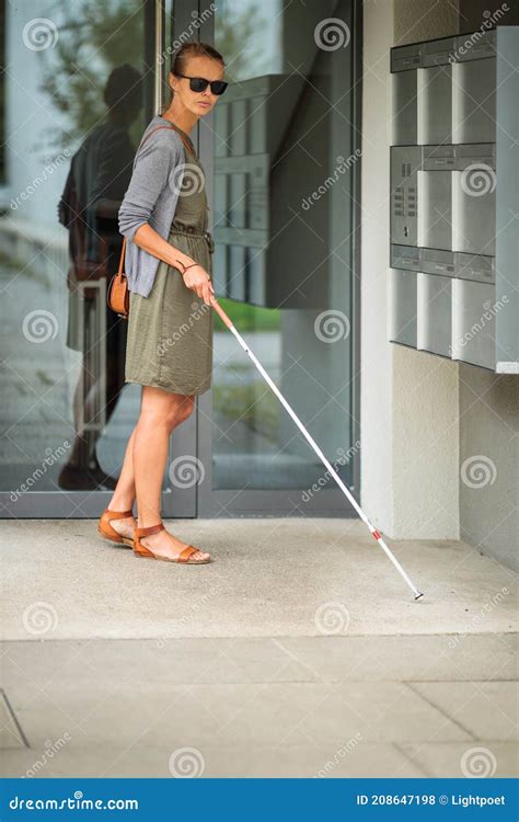 Blind Woman Walking On City Streets Using Her White Cane Stock Photo
