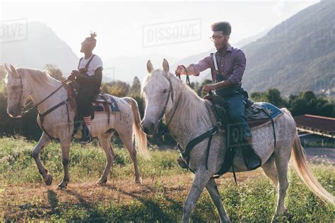 So how do you take charge or even be ready for it? Two young men horse riding in field, Primaluna, Trentino ...