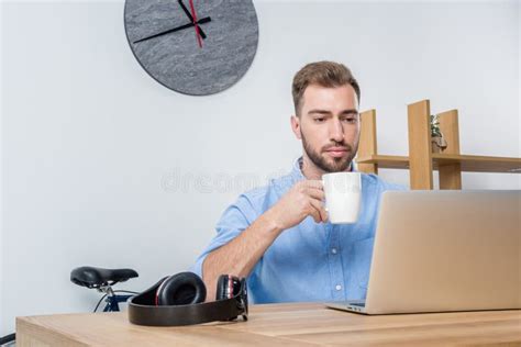 Young Businessman Drinking Coffee While Working With Laptop In Office