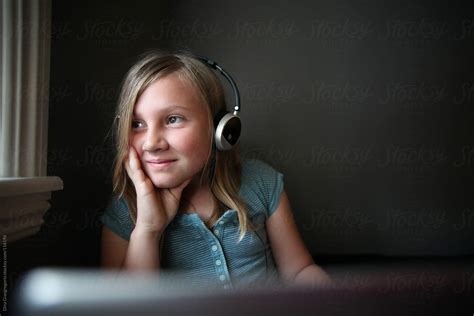 Young Girl In Bedroom Using Laptop And Headphones Del Colaborador De