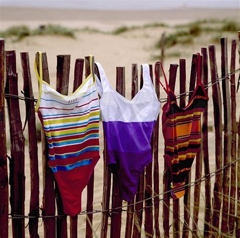 Image Close Up Of Striped Swim Suits Hanging Out To Dry On Wooden Fence In Front Of Sand Dunes