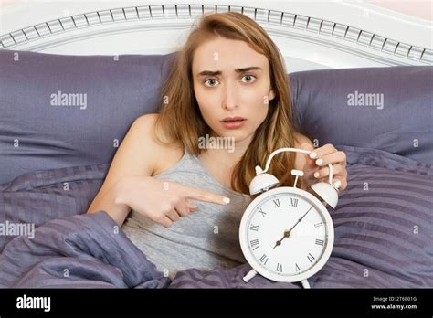 Shocked Young Woman Waking Up With Alarm Girl Point On Clocks In Bed