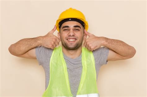 Free Photo Front View Male Builder In Yellow Helmet Posing Showing Like Sign On Light Background