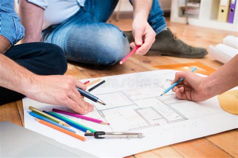 Team Of Architects Sitting On Floor With Construction Plans Stock Image